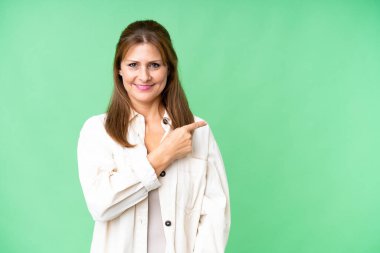 Middle age woman over isolated background pointing to the side to present a product