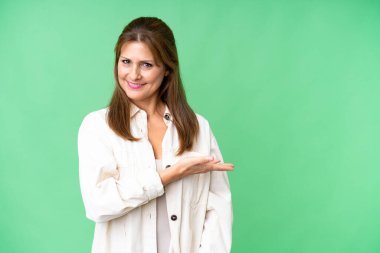 Orta yaşlı bir kadın soyutlanmış bir arka planda gülümserken bir fikir sunuyor.