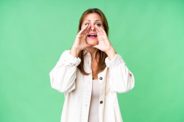 Middle age woman over isolated background shouting and announcing something