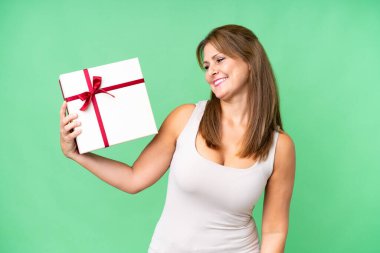 Middle age caucasian woman holding a gift over isolated background with happy expression