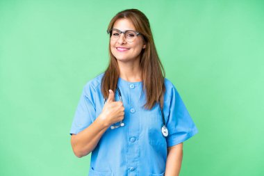 Middle age nurse woman over isolated background giving a thumbs up gesture