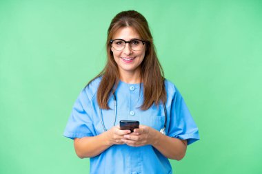 Orta yaşlı bir hemşire cep telefonuyla mesaj yolluyor.