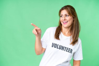 Orta yaşlı, izole edilmiş bir geçmişi olan gönüllü bir kadın parmağını yana uzatıp bir ürün sunuyor.