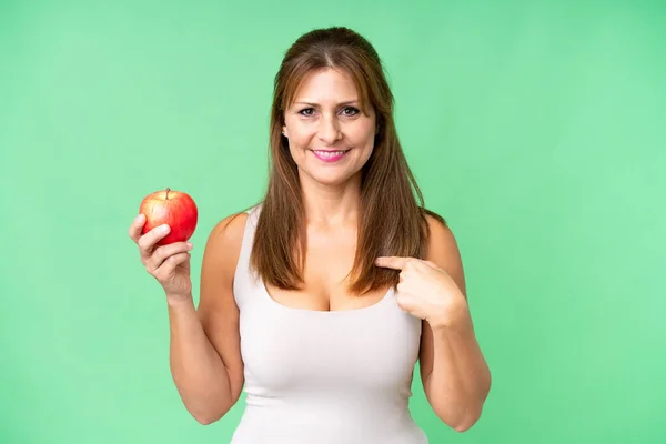 一个中年妇女 有一个苹果过孤立的背景 满脸惊讶的表情 图库图片