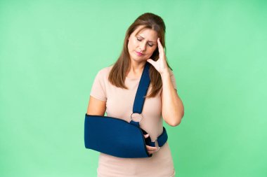 Orta yaşlı, kırık kollu ve izole edilmiş arka planda baş ağrısı olan bir kol askısı takıyor.