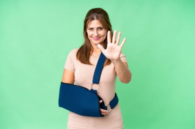 Orta yaşlı, kırık kollu ve izole edilmiş arka planda kol askısı takıyor. Beş parmaklı sayıyor.