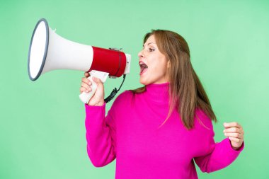 Middle age woman over isolated background shouting through a megaphone to announce something in lateral position