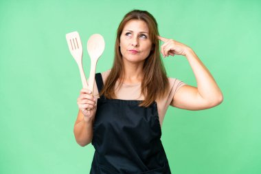 Kafkasyalı orta yaşlı bir kadın izole edilmiş arka planda iğne tutuyor. Şüpheleri ve düşünceleri var.