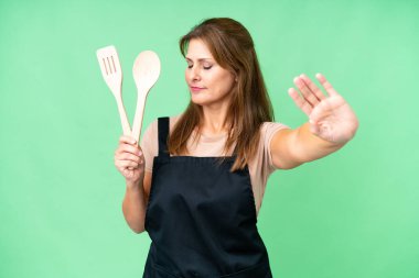 Orta yaşlı, beyaz bir kadın, izole edilmiş arka planda bir iğne tutuyor. Durma hareketi yapıyor ve hayal kırıklığına uğruyor.