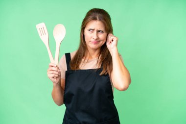 Kafkasyalı orta yaşlı bir kadın izole edilmiş arka planda iğne tutuyor hayal kırıklığına uğramış ve kulaklarını kapatmış.