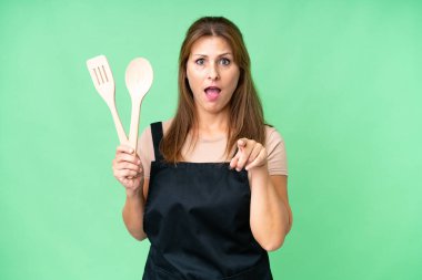 Kafkasyalı orta yaşlı bir kadın izole bir arka planda merdane tutuyor şaşırmış ve ön tarafı işaret ediyor.