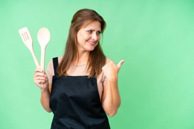 Orta yaşlı, beyaz bir kadın, izole edilmiş arka planda merdane tutuyordu. Ürünü sunmak için yan tarafı gösteriyordu.