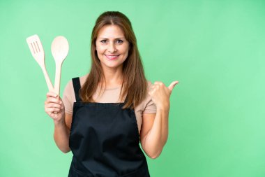 Orta yaşlı, beyaz bir kadın, izole edilmiş arka planda merdane tutuyordu. Ürünü sunmak için yan tarafı gösteriyordu.