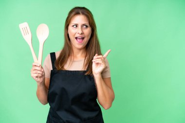 Orta yaşlı, beyaz bir kadın, izole edilmiş arka planda bir iğne tutuyor. Çözümü bulmak için parmağını kaldırıyor.