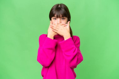 İzole edilmiş arka planda küçük beyaz kız elleriyle ağzını kapatıyor.