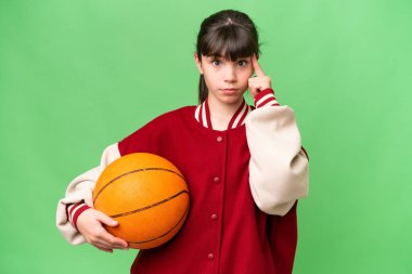 İzole edilmiş arka planda basketbol oynayan küçük beyaz kız bir fikir düşünüyor.