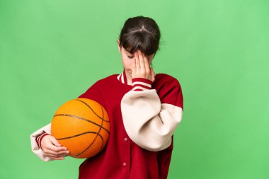 İzole edilmiş arka planda basketbol oynayan küçük beyaz kız yorgun ve hasta bir ifadeyle.