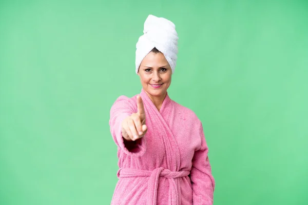 中年Caucasian女性でバスローブ上の隔離された背景ショーと持ち上げる指 — ストック写真