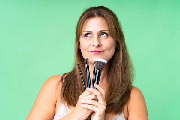 Medelålders Kvinna Över Isolerad Bakgrund Håller Makeup Borste Och Tittar — Stockfoto