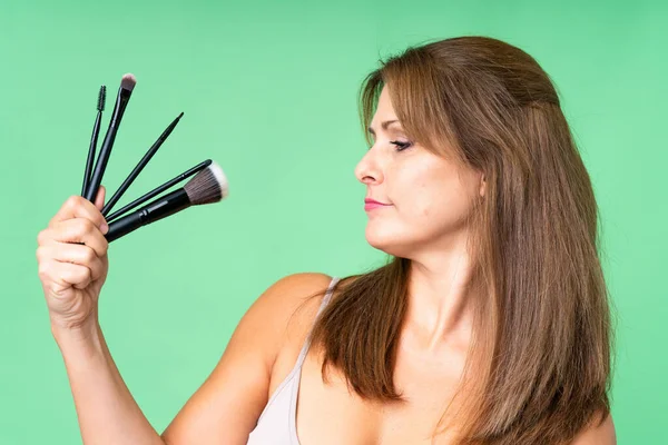 Mulher Meia Idade Sobre Fundo Isolado Segurando Escova Maquiagem Olhá — Fotografia de Stock