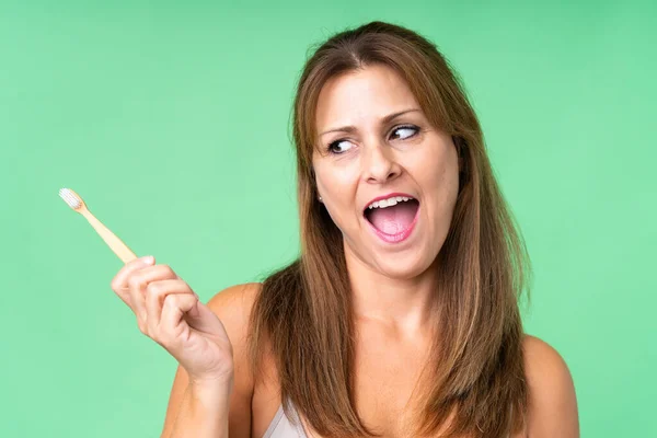 Midaldrende Kvinde Isoleret Baggrund Med Tandbørste Overrasket Udtryk - Stock-foto