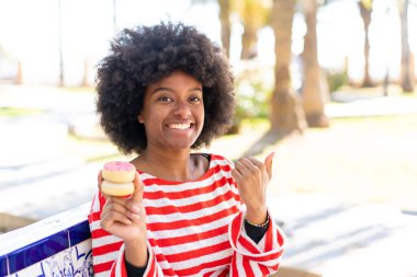 Afro-Amerikalı bir kız açık havada bir ürün sunmak için bir tarafı işaret ediyor.