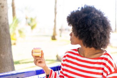 Afrika kökenli Amerikalı bir kız arka tarafta donut tutuyor.