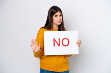 Young Brazilian woman isolated on white background holding a placard with text NO and doing stop sign