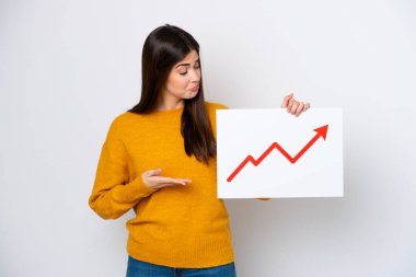 Beyaz arka planda izole edilmiş genç Brezilyalı kadın elinde büyüyen bir istatistik oku sembolü olan bir tabela tutuyor ve onu işaret ediyor.