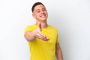 Beyaz arka planda izole edilmiş genç Brezilyalı adam iyi bir anlaşma için el sıkışıyor.