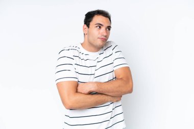 Beyaz arka planda izole olmuş genç beyaz bir adam omuzlarını kaldırırken şüpheyle hareket ediyor.