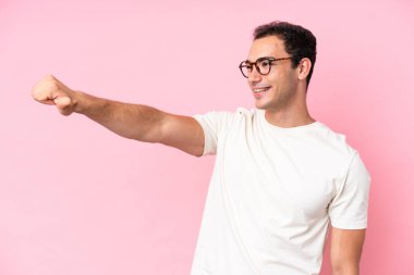 Pembe arka planda izole edilmiş genç beyaz bir adam baş parmak hareketi yapıyor.