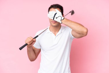 Genç golfçü adam pembe arka planda izole edilmiş gözleri elleriyle kapatıyor. Bir şey görmek istemiyorum.