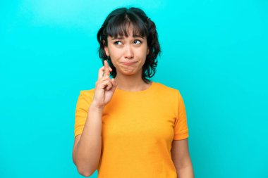 Arjantinli genç bir kadın mavi arka planda izole edilmiş, şans diliyor ve en iyisini diliyor.