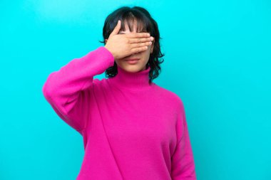 Arjantinli genç bir kadın mavi arka planda tek başına, gözlerini elleriyle kapatıyor. Bir şey görmek istemiyorum.