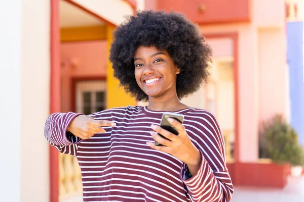 Ragazza Afroamericana Utilizzando Telefono Cellulare All Aperto Indicandolo — Foto Stock