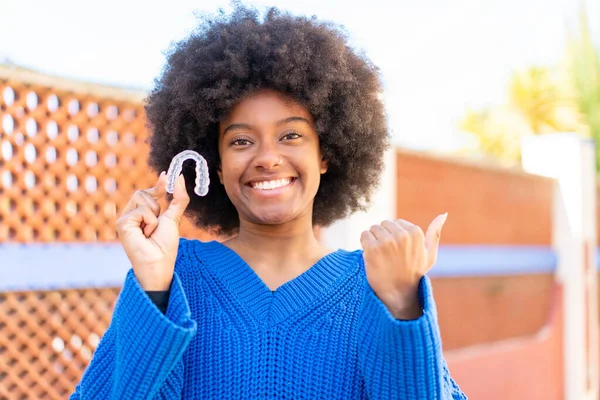 African American Girl Holding Invisible Braces Outdoors Pointing Side Present — Stock Photo, Image