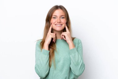 Beyaz arka planda izole edilmiş genç beyaz kadın mutlu ve hoş bir ifadeyle gülümsüyor.