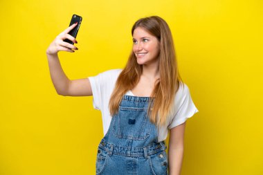 Sarı arka planda izole edilmiş beyaz bir kadın selfie çekiyor.