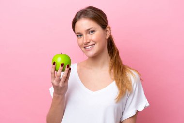 Genç beyaz kadın pembe arka planda bir elmayla izole edilmiş.