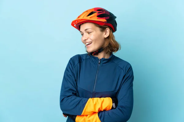 Junge Radfahrerin Isoliert Auf Blauem Hintergrund Zur Seite Schauend Und — Stockfoto
