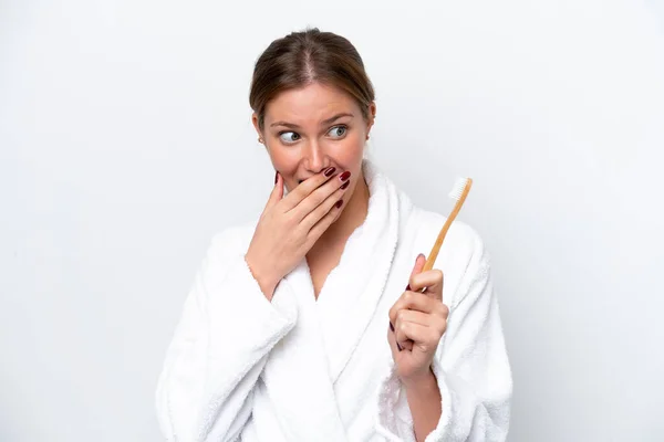 Young caucasian woman brushing teeth isolated on white background with surprise and shocked facial expression