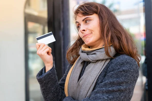Mujer Morena Sosteniendo Una Tarjeta Crédito Aire Libre Con Expresión —  Fotos de Stock