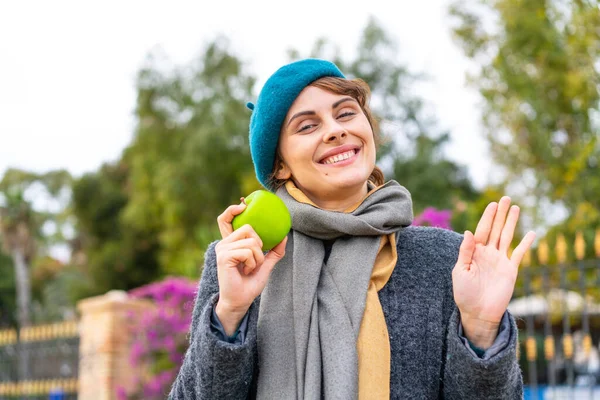 Mujer Morena Con Una Manzana Aire Libre Saludando Con Mano — Foto de Stock