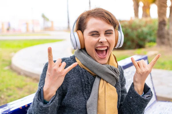 Bruneta Žena Venku Poslouchá Hudbu Dělat Rockové Gesto — Stock fotografie