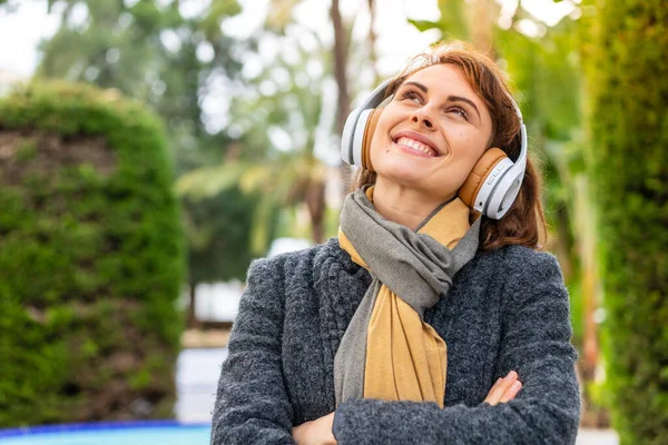 Mujer Morena Escuchando Música Con Auriculares Aire Libre Mirando Hacia —  Fotos de Stock
