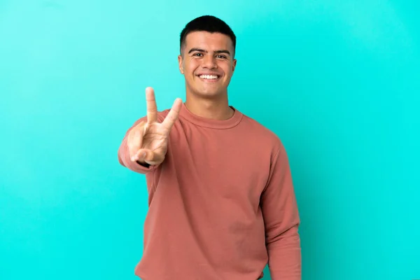 Jonge Knappe Man Geïsoleerde Blauwe Achtergrond Glimlachen Tonen Overwinning Teken — Stockfoto