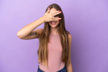 Genç Litvanyalı bir kadın, mor arka planda izole edilmiş, gözleri kaplanmış ve gülümsüyor.