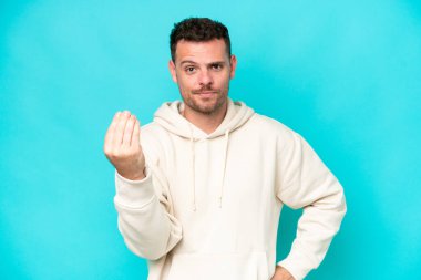 Mavi arka planda izole edilmiş beyaz, yakışıklı bir genç İtalyan jesti yapıyor.