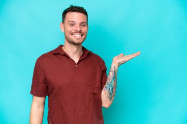 Beyaz tenli yakışıklı, mavi arka planda izole edilmiş bir adam. Elinde bir ilan vermek için fotokopi odası hayali var.